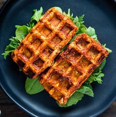 two waffles on top of lettuce on a blue plate next to a fork