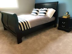 a bedroom with blue walls and carpeted flooring, a black bed in the middle