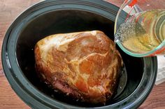 a close up of a meat in a crock pot next to a glass of water