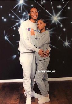 a man and woman posing for a photo in front of a wall with stars on it