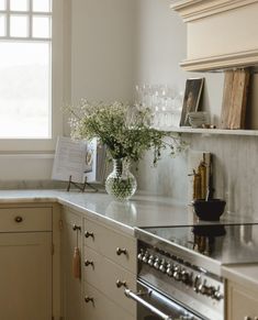 a vase with flowers is sitting on the counter in a kitchen next to an oven