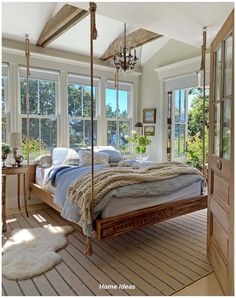 a bedroom with a bed, windows and rugs on the floor in front of it