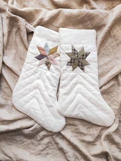 two quilted stockings laying on top of a bed covered in sheets and blankets, one with an appliqued star