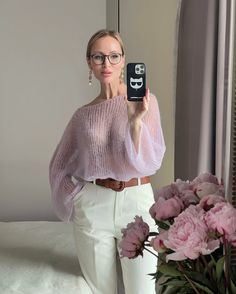 a woman taking a selfie with her cell phone in front of a bouquet of flowers