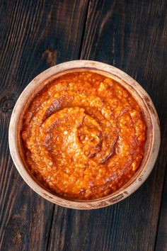 a bowl filled with sauce on top of a wooden table