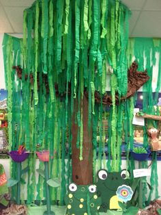 a tree with green tissue paper hanging from it's trunk and two faces on the branches