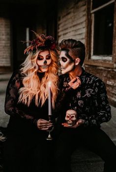 two people dressed in skeleton makeup holding a candle