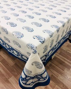 a blue and white table cloth with an elephant design on it, sitting on a wooden floor