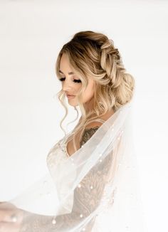 a woman in a wedding dress with a veil over her head and tattoos on her arm