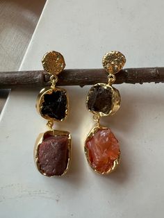 A symbol of feminism and elegance! Love the beautiful one-of-a-kind natural gemstones earrings on a gold plated base. This gorgeous pair of earrings has the power to be one little thing that can make you feel unique. Handcrafted by our skilled Indian craftsmen from Jaipur Material: Brass, gold plated, amethyst, smoky quartz carnelian stones  Length of earrings: 5 cms  Width of earrings: 2 cms  Weight of the earrings: 14 grams per pair Natural Stone Brass Earrings For Gift, Gold Brass Earrings With Gemstone, Brass Earrings With Natural Stones, Luxury Natural Stone Drop Earrings, Luxury Brass Earrings With Natural Stones, Gemstones Earrings, Smoky Quartz Earrings, Carnelian Stone, Brass Gold