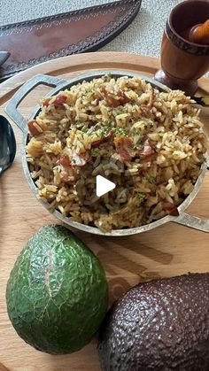 an avocado and rice dish on a wooden tray with spoons, knife and utensils