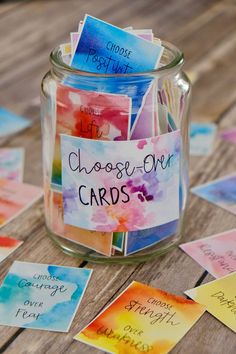 a jar filled with cards on top of a wooden table