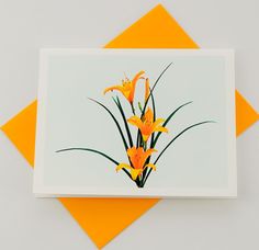 a card with yellow flowers on it sitting on top of an orange and white envelope