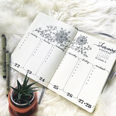 an open planner sitting on top of a white blanket next to a potted plant