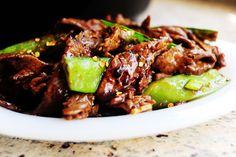 a plate full of food with meat and cucumbers on it, sitting on a table