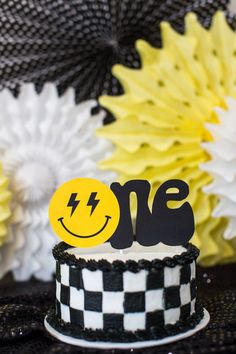 a black and white cake topped with a yellow smiley face on it's top