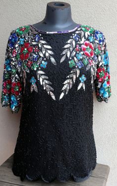 Exquisite piece of work in this garment. It is embellished with thousands of sequins and beads.  100% silk and embellished with colorful flowers.  Fully lined in polyester. Has a zipper at the back of the neck for easy on/off. Stunning. Gorgeous top for that special event. You can pair it with jeans for a Bohemian look or dress it up with a skirt or dress pants.  This vintage work of art top is in very good condition and has been dry cleaned and stored well. Looks like all the beads are there, but you can never be sure. Overall, looks great. If you tried to purchase such workmanship in today's market, you would pay well over $200. Ladies Size 12 Here are some measurements to help you compare it to an item that fits you well at home: Shoulder seam to Shoulder seam - 19" Armpit to armpit - 1 Festive Embellished Sequin Fabric For Parties, Embellished Sequin Fabric For Formal Holiday Events, Embroidered Fitted Sequin Fabric For Party, Embellished Silk Sequin Evening Dress, Elegant Multicolor Embellished Sequin Dress, Embellished Sequin Fabric For Party Celebrations, Fitted Sequin Embellished Fabric For Evening, Embellished Sequin Dress For Party Season Celebrations, Multicolor Embellished Sequin Fabric For Festive Season