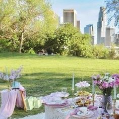 a table set up for a tea party with pink flowers and desserts on it