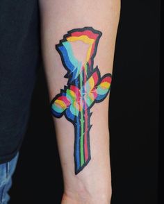 a colorful cross tattoo on the arm