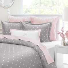 a bed with pink and gray sheets and pillows