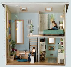 two people are sitting on the floor in a dollhouse with stairs leading up to the second floor