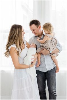 a man and woman holding two babys in their arms