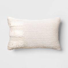 a white pillow with fraying on the front and back, against a gray background