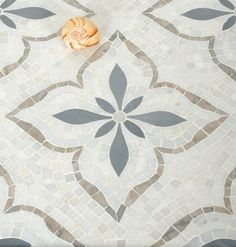 an orange object is sitting on the floor in front of a tile pattern that looks like a flower