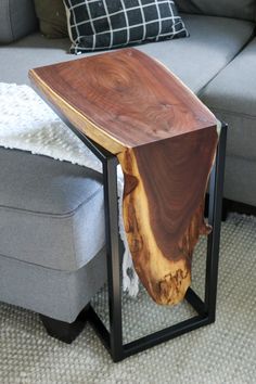 a wooden table sitting on top of a metal frame in front of a gray couch