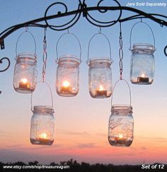 mason jars hanging from a metal rod with candles in them