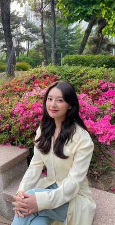 a woman sitting on a bench in front of flowers