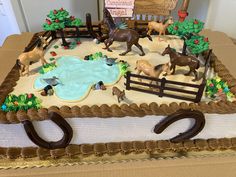 a sheet cake with horses on it in the shape of a farmyard and pond