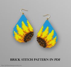 a pair of earrings with yellow and blue flames on it, in the shape of a tear