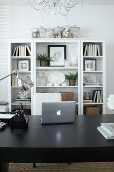 a laptop computer sitting on top of a wooden desk in front of a book shelf