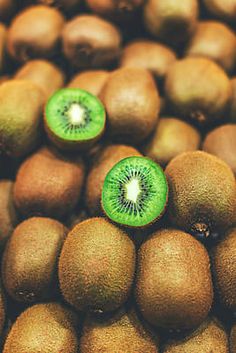 kiwi fruit with one cut in half sitting on top of each other