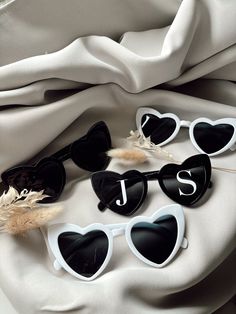 four pairs of heart shaped sunglasses with the letter j and s on them sitting on a white cloth