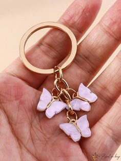 a hand holding a pink and white flower keychain in it's palm