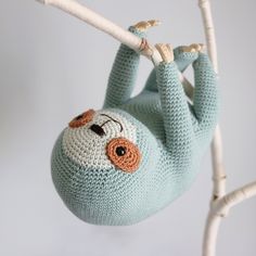 a crocheted stuffed slotty hanging from a twig on a tree branch