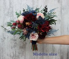 a hand holding a bouquet of flowers on top of a wooden table with the words middle size written below it