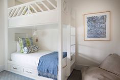 a white bunk bed with blue and green pillows