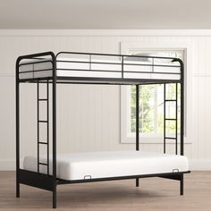 a black metal bunk bed with white mattress and ladders on the bottom level, in an empty room