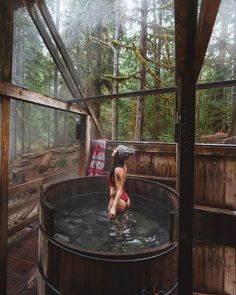 a woman in a red bathing suit sitting on top of a barrel filled with water