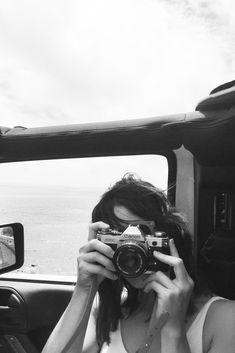 a woman taking a photo in the back of a truck with her camera up to her face