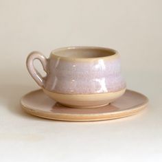 a white cup and saucer sitting on top of a wooden plate next to each other