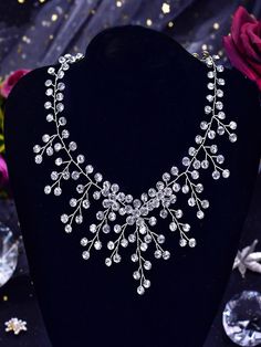 a necklace is displayed on a mannequin in front of flowers and crystal stones