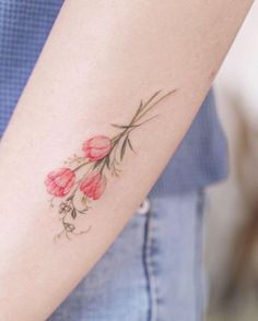 a woman's arm with red flowers on it and leaves coming out of the side