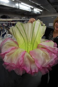 a woman is holding up a dress made out of tulle and organel flowers