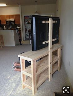 a person laying on the floor in front of a television and entertainment center that is made out of wood