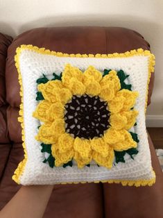 a crocheted sunflower pillow sitting on top of a brown couch