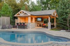 a backyard with a pool, bar and grill area next to the outdoor living space